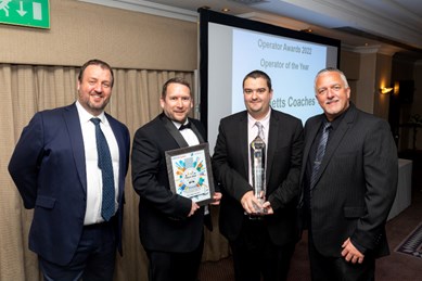 Four men holding certificates and awards at award ceremony